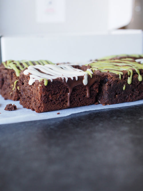 Close up of gluten free fudge brownies with white chocolate and matcha drizzle topping
